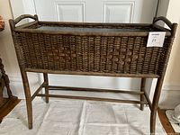 Front view of wicker planter showing rectangular basket with aluminum tray and wooden legs.