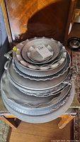 Stack of 9 aluminum platters, trays, and bowls with varying sizes and scalloped edges.