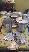Overall view of hammered aluminum serving ware set including large chafing pot, pitcher, bowls, platters, ice bucket, and serving trays.