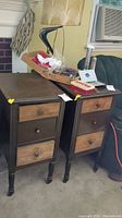 Pair of vintage nightstands next to each other in a room with various items on top and around them.