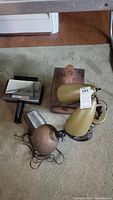 Photo showing two MCM gooseneck lamps in beige and bronze next to a wooden shoe shine box on carpeted floor.