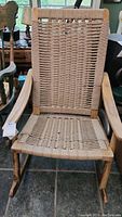Front view of wooden rocking chair with woven wicker seat and backrest, showing overall condition and structure.
