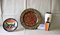 Two carved soapstone figures on the left and right with a decorated 12-inch plate in the middle, all with East African design influences
