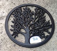 Front view of circular Tree of Life wooden wall hanging with intricate leaf and branch carving, placed on stone surface.