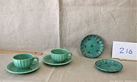 Two green cups with matching saucers by Granit, Hungary, displayed alongside two turquoise scalloped butter dishes by Gustavsberg, Sweden.