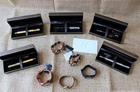 All five boxed pens and five wooden Patina Canada wristwatches arranged on a flat surface showing the whole collection.