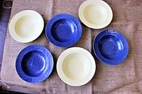Top view of six bowls arranged with three blue and three yellow bowls alternating on a furniture cover.