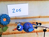 Close-up photo showing detailed blue bird figure on garden stake with flower accent