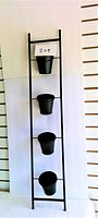 Full photo of vertical garden ladder with four black removable pots from top to bottom against white background.