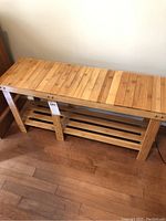 Front view of wooden bench showing slatted top surface and lower shelf with wide slats.