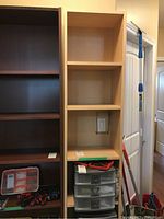 Full view of the bookshelf next to another shelving unit, showing height and shelf configuration with items removed from this bookshelf.