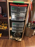 Plastic storage containers and shelves with tool organizers visible, showing multiple drawers for small parts storage.