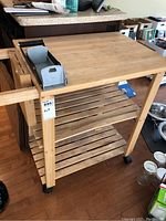 Wooden kitchen cart showing top view with can crusher and utensil holder attached on one side.