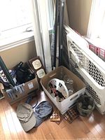 Photo showing gloves, caps, clock, glassware, curtain rods, safety gate, wooden puzzles and decorative boxes grouped on floor near window