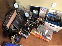 Full overview of various office items including desk lamps, shoulder bags, staplers, tape dispensers, desk caddy with scissors, and clock bookends all placed on a hardwood floor.