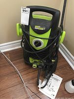 Front view of the green and black Power IT! high pressure washer with coiled hose and attached wand, showing control dial and handle.