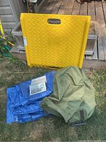 Photo showing yellow Two Eagle step ramp, blue tarp, green bag and aluminum plates on grass outdoor setting.