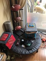 Wide shot showing mini trampoline, metal stand with footballs, cooler bags, basketball hoop backboard, and some accessories.