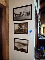 Three framed vintage prints mounted on a cream textured wall showing all items in the lot.
