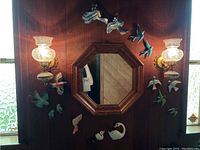 Full wall view with mirror, sconces, and ceramic bird decorations