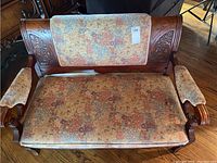 Full frontal view showing the entire upholstered bench with carved wooden sides and floral fabric.