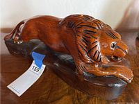Side view of the carved wooden lion statue showing its color, carving details, and base condition.