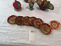Overall view of 7 round decorative vintage coasters with scalloped edges and 4 different styled flower vases on white tablecloth.