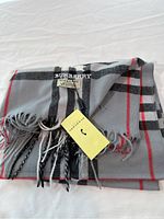 Folded grey cashmere scarf showing check pattern and fringed edge
