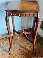 Square wooden occasional table with decorative inlaid top and carved legs shown from an angle.