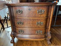 Front view of antique wash stand showing three drawers with ornate brass handles and carved wooden legs.
