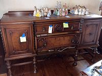 Front view of vintage wooden buffet showing two drawers and two cabinet doors with carved decorative details and turned legs