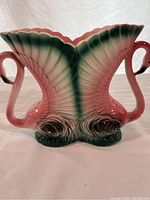 Full view of the ceramic vase featuring two flamingo heads and a fan feather design detail in pink and green colors.