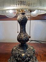 Close-up image focusing on the intricately designed metal base of the lamp showing ornate, raised decorative elements.