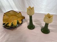 Two Henriksen tulip-shaped pottery candlesticks and one leaf-shaped pottery dish shown together.