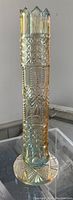 Tall crystal vase with geometric and star cut patterns and carnival coloration from top to base.