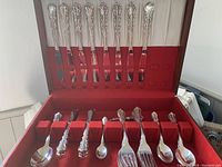 Full view of open box with top tray showing 8 dinner knives and bottom showing assorted forks, spoons and spreaders