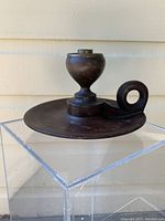 Front view of the large antique wooden candle holder showing its wide base, elevated candle socket, and loop handle