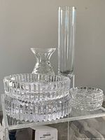 View of all five crystal glassware pieces displayed together on clear shelving, showing shapes and relative sizes.