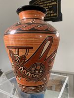 Front angle view showing bird motif on Mexican pottery vase with black painted rim and red clay body.