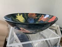 Side view of the pottery bowl showing the painted floral design and shape.