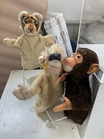 Photo showing all three Steiff puppets (tiger, chimpanzee, orangutan) on white surface, arranged side by side