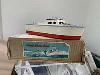 Model motor boat on original cardboard box showing boat colors and box label.