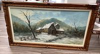 Front view of the framed acrylic landscape painting showing wooden houses in a winter setting.