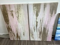Two abstract stretched canvas paintings side by side showing vertical brush strokes in muted colors.
