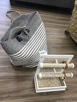 Photo showing the large black and white woven bag along with the white wooden jewelry holder and two bracelets placed inside the holder.