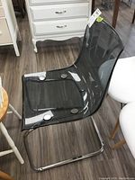 Full side and front angled view of the acrylic chair with visible metal base and translucent seat.