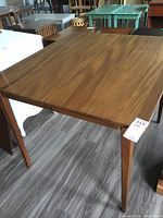 Wood dining table without the leaf, showing smooth finish and tapered legs.