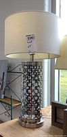 Full view of metal base table lamp with white drum shade, showing height and style.
