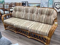 Full view of the three-seater rattan sofa with striped fabric cushions