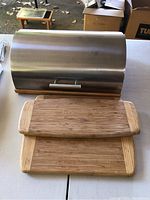 Metal breadbox with two bamboo cutting boards placed in front, showing size and condition